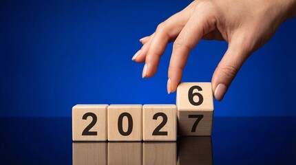 A hand carefully selects a wooden cube with the number six completing the sequence representing the year 2027 high quality professional