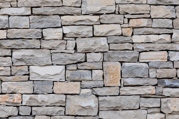 Fototapeta premium Rough cut light gray and beige stacked stone wall texture