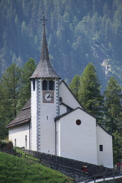 Church with steeple in forested mountain landscape under clear blue sky