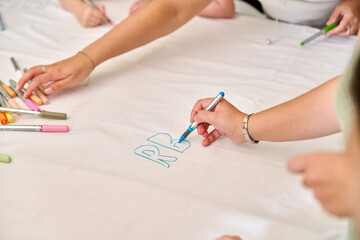 Hands drawing with markers on large white paper surface