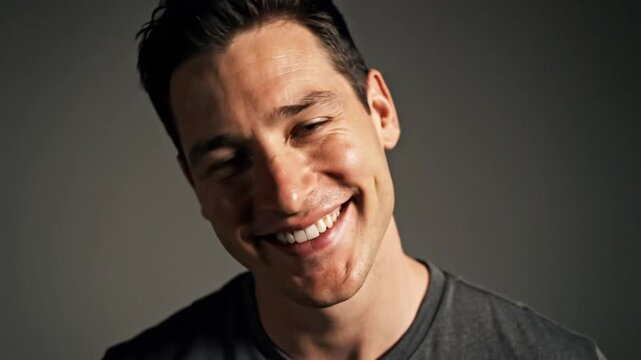 Happy man with a bright smile posing against a soft gray backdrop, portrait photography