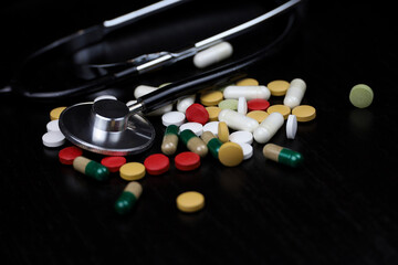 Health care and cardiology, stethoscope and pills on dark table. Concept of diagnosis, treatment of heart diseases