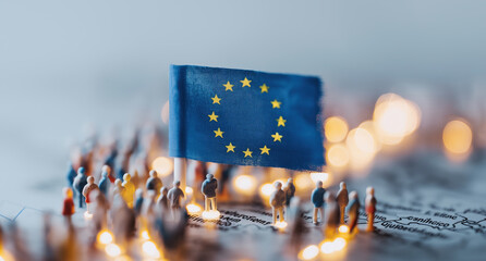 Miniature European Union flag surrounded by tiny figurines representing diverse citizen community.