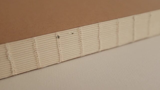 Aesthetic closeup slow motion video of an old book binding. Open binding made by sewing threads. Concept of timeless wisdom and education.