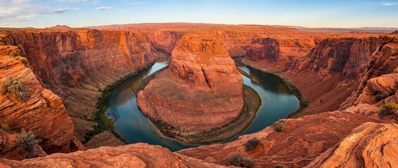 A breathtaking panoramic view of a horseshoe bend in a desert landscape, the winding river carved through sandstone, displaying the power of nature's sculpting hand.