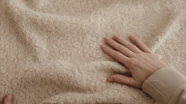 Closeup aesthetic video of hands touching soft wool sweater. Ivory fluffy knitted sweater for cold winter. Appreciating pleasant texture of high quality clothes. Soft and cosy clothes. 