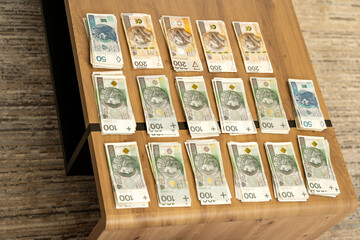 high angle view of many stacks of polish zloty (PLN) banknotes arranged neatly on a wooden table representing wealth, financial success, savings, and cash investment