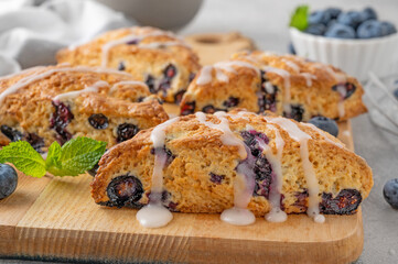 Blueberry scones with lemon glaze on top on a gray concrete background. Delicious breakfast.