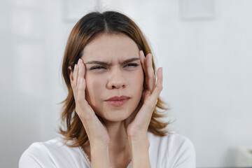 Women suffering from headache and holding her temples with discomfort, showing migraine pain or...