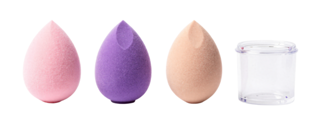 Photograph of four objects in a row: three textured, teardrop-shaped sponges in pink, purple, and beige, and a clear glass cup on the right.