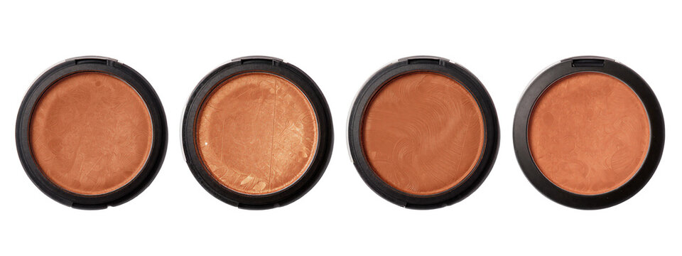 Four circular, black-cased eyeshadows with varying shades of warm brown and copper, arranged horizontally.