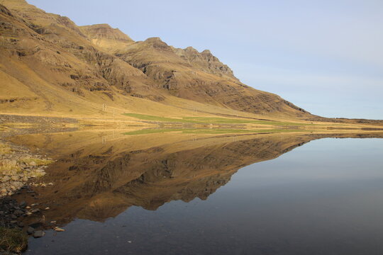 Mountain range reflected in calm water under clear blue sky
