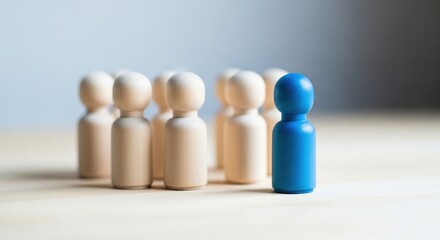 Blue wooden figure standing apart from group on table background, leadership and individuality concept, standing out from crowd, uniqueness and business differentiation
