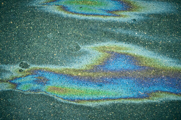 Bright oil spill on the road surface, generating an intriguing abstract background.