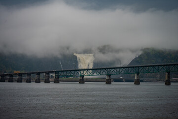 Waterfall behind bridge in foggy weather