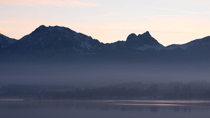Obraz premium Sunset on Lake Hopfen in Bavaria Germany in Winter 2025 - Great Orange and Blue - Beautiful Alps with Great LIght and Ice - High quality photo