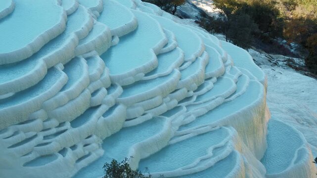 Brilliant blue terraced pools of Baishuitai reflect surrounding mountains and forests, revealing a sacred limestone landscape unique to Yunnan, China.