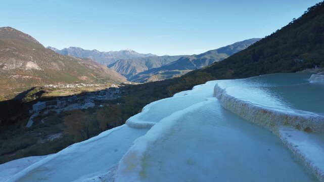Brilliant blue terraced pools of Baishuitai reflect surrounding mountains and forests, revealing a sacred limestone landscape unique to Yunnan, China.