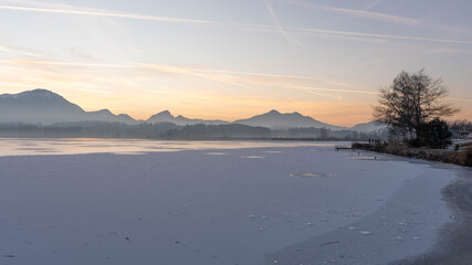 Fototapeta premium Sunset on Lake Hopfen in Bavaria Germany in Winter 2025 - Great Orange and Blue - Beautiful Alps with Great LIght and Ice - High quality photo