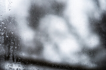 Close up of water droplets and condensation on a fogged window during rain. Soft focus and natural lighting create a calm, peaceful atmosphere.