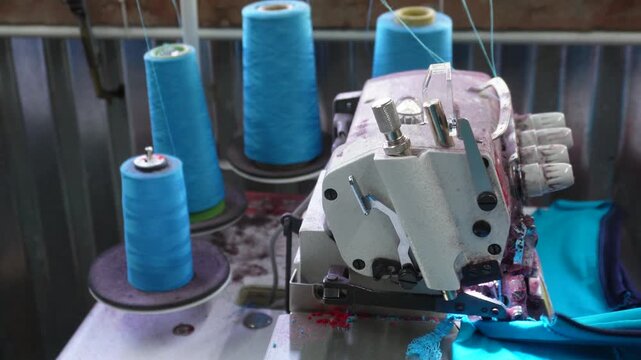 Sewing machine, also known as a serger, with several spools of blue thread. These machines are used to create professional, finished seams on fabric edges. 