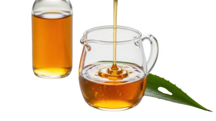 Amber liquid pouring into glass pitcher next to bottle and aloe vera leaf golden syrup