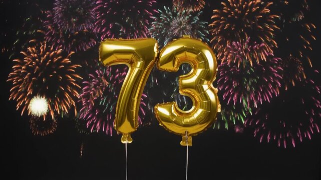 Gold balloon number 73 with fireworks in the background. Festive scene for birthday or anniversary party