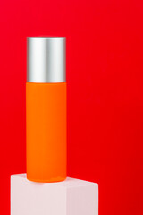 Cosmetic product in tube, bottle, lotion or serum with stylish props on red background. 