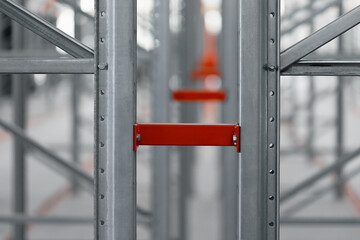 Metal warehouse pallet or shelf rack, close-up of the connection node. Vertical perforated rack and horizontal beams, painted orange. Industrial logistics structure for warehouses, stores, archives.