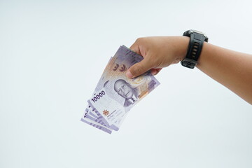 Hand holding Indonesian rupiah banknote on white background representing cash payment, personal finance, income, and financial transaction with clean minimal composition.