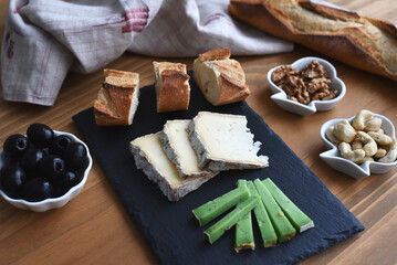 Fototapeta premium Aperitif with cheese bread olives and nuts on wooden table