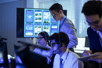Diverse professional team with headsets working in a modern office. Managers collaborate on digital mobile app data while support staff provide technical assistance at a high-tech service center
