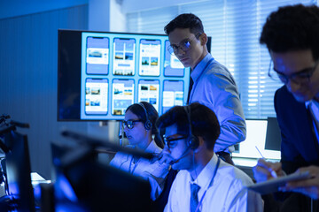 Diverse professional team with headsets working in a modern office. Managers collaborate on digital mobile app data while support staff provide technical assistance at a high-tech service center