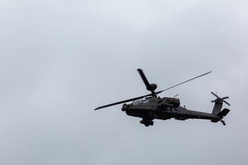 Apache attack helicopter or AH64 can be seen in flight against a dark cloud background as it flies over Salisbury plain