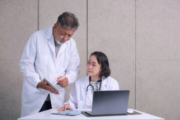 Senior medical experts having serious professional discussion consulting over digital tablet looking focused