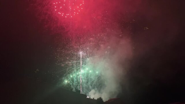 Multiple fireworks exploding with bright colors and thick smoke during a night celebration