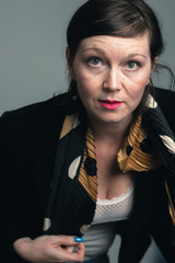 Portrait of attractive young business woman looking at camera with collected dark hair dressed in black jacket. Business concept.