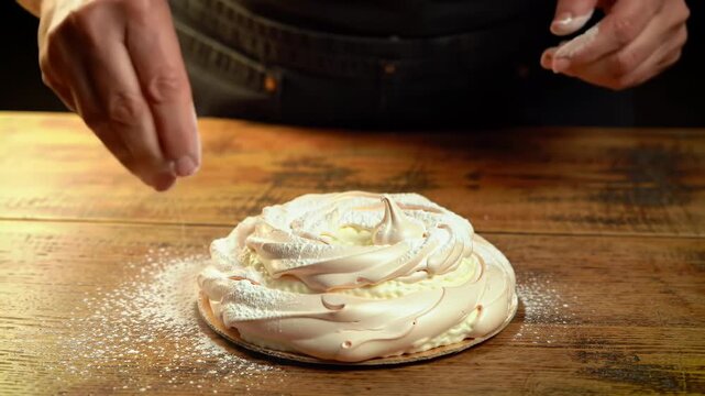 Person preparing meringue dessert on wooden table with powdered sugar - Powered by Adobe