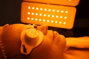 Client receiving a skincare treatment under orange light therapy
