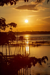 Golden Sunset Over Calm Lake with Fishing Nets and Reflections at Dusk