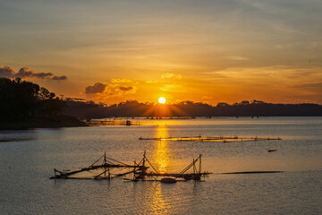 Golden Sunset Over Calm Lake with Fishing Nets and Reflections at Dusk