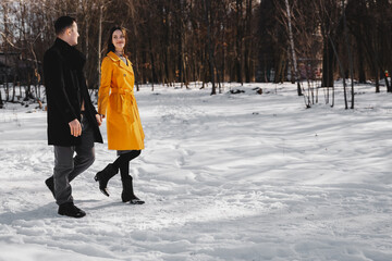Couple enjoying a winter walk in a snowy park during daylight