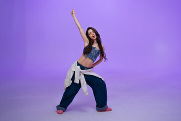 Dancer expressing movement against a purple backdrop in urban attire