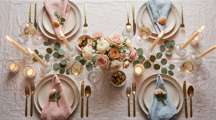 Elegant table setting with pastel roses, candles, and gold cutlery on a neutral linen tablecloth