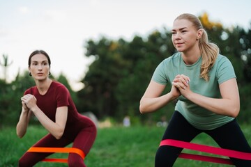 Two women practicing strength training outdoors in a park on a sunny day