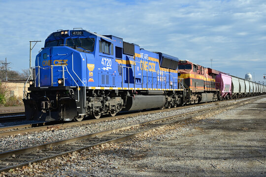 A specially painted CSX Transportation locomotive is on the point of a train of empty sand hoppers that originated in West Virginia as it approached its destination at a suburban Chicago rail yard.