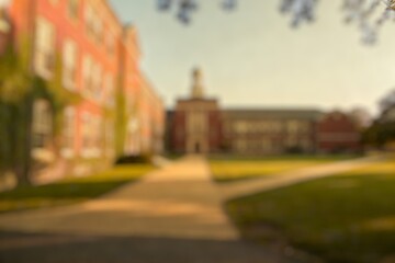 Obraz premium Blurred Background of Modern architectural design of a red brick building with clock tower and glass facade surrounded by trees and greenery in a clear blue sky. 