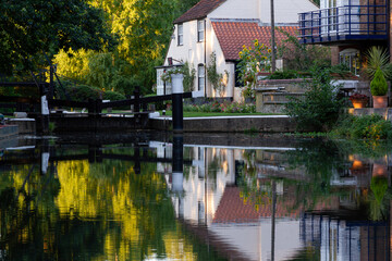 Lock keeper&rsquo;s cottage reflected in calm water on the River Wey Navigation, Surrey