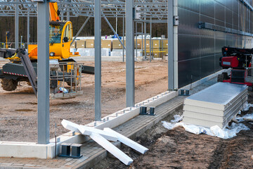 Industrial construction site with steel frame and stacked sandwich wall panels ready for installation