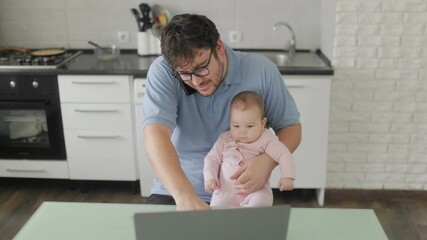 Father holding baby while working and talking on phone